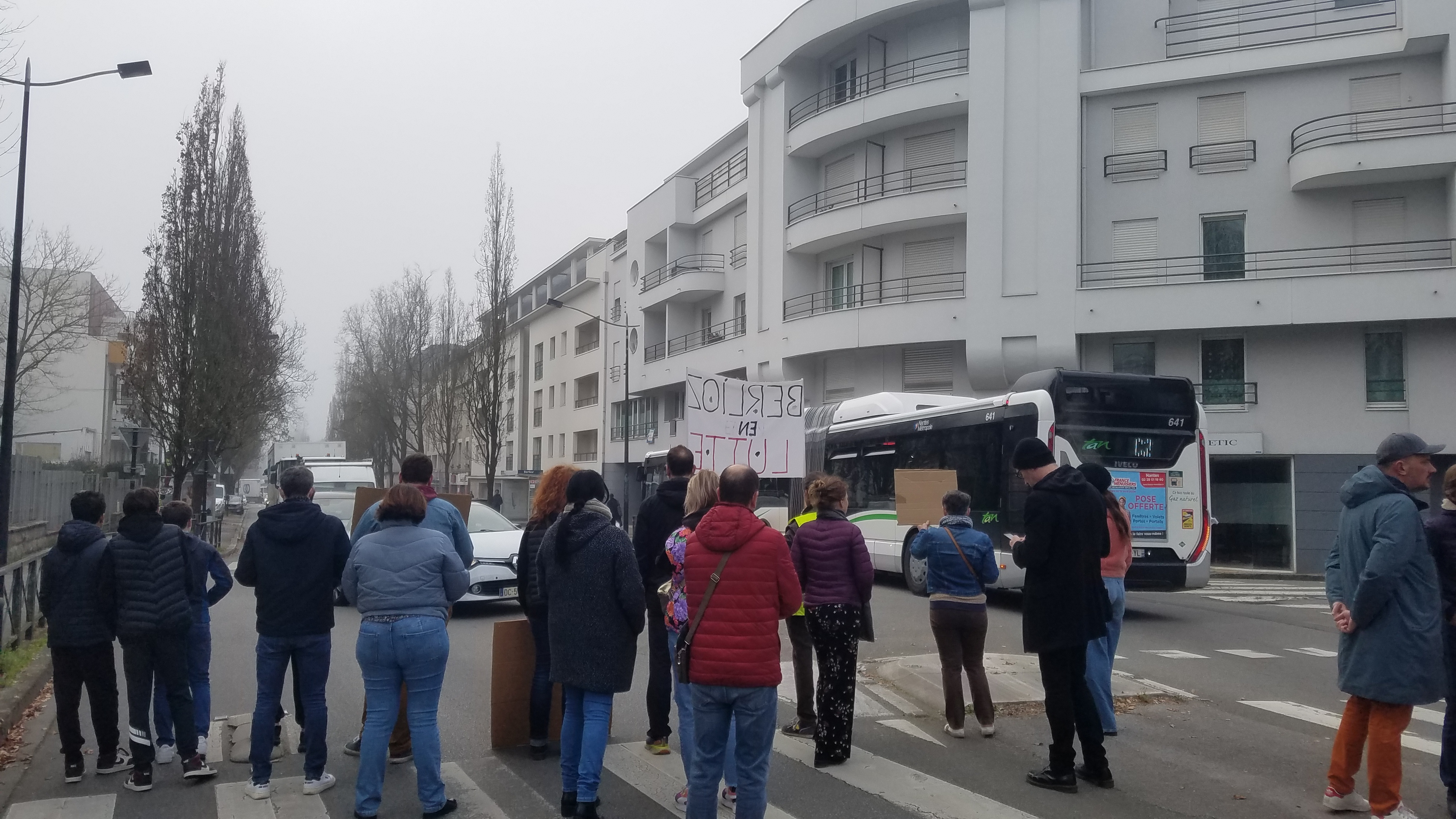 Photo d'un regroupement de parents de dos limitant la circulation avec des pancartes